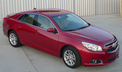 A three-quarter front view of a red 2013 Chevrolet Malibu Eco A three-quarter front view of a red 2013 Chevrolet Malibu Eco