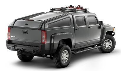 A three-quarter rear view of a 2009 H3T with a slanted bed cover and a ski and snowboard rack