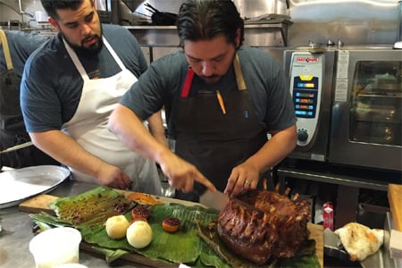 Chef Ray Garcia carving out a rack of heritage pork in preparation for Cochon 555