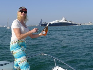 Sophie Gayot sabraging a bottle of Champagne on the bow of Serene, Yury Scheffler's yacht