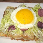 Caramelized onion and frisee tart with olives, gruyere and fried egg